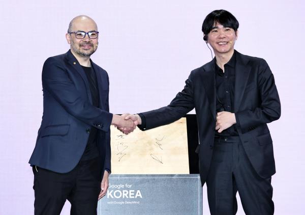 Google DeepMind CEO Demis Hassabis (left) and Go grandmaster Lee Se-dol shake hands after signing a Go board during the Google for Korea 2026 event at The Westin Josun Seoul, Wednesday. (Yonhap)
